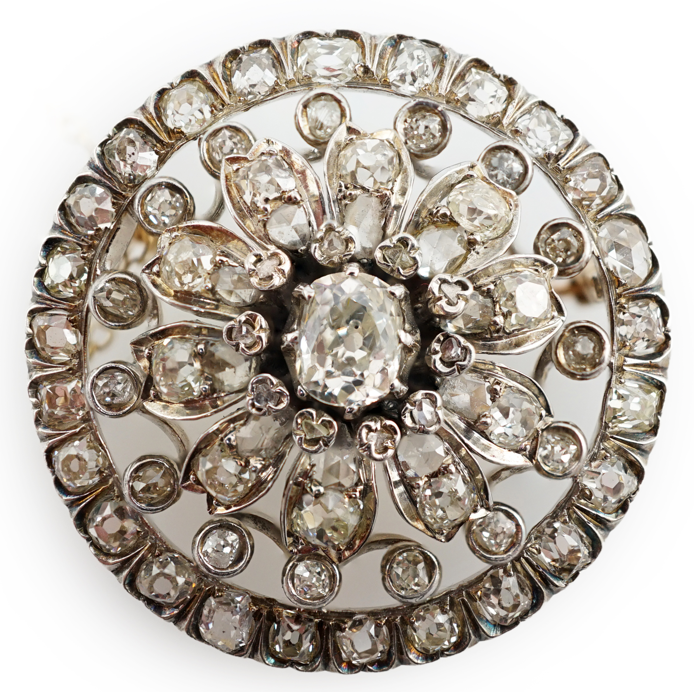 An Edwardian pierced gold and diamond cluster set circular brooch, with central cushion cut stone, diameter 34mm, gross weight 14.4 grams. Condition - fair to good
